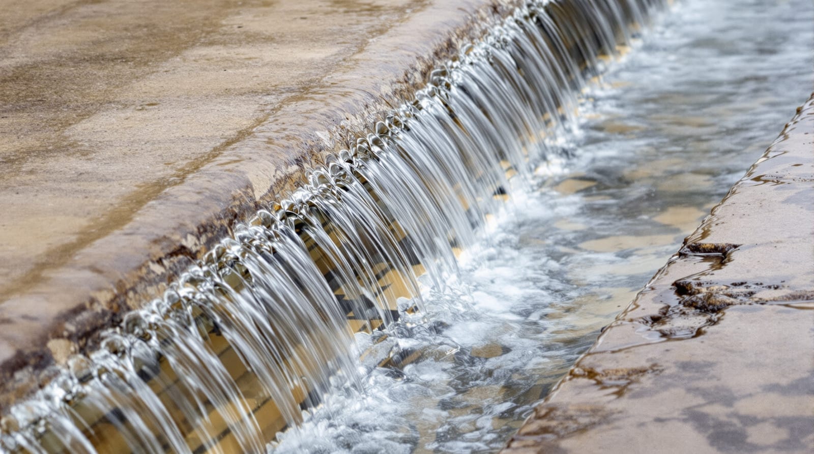 Water flowing over a low stone weir into a channel